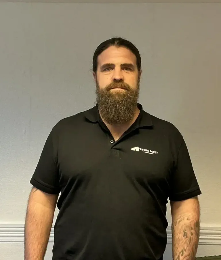 Bildet viser en mann med mørk skjorte med Rygja Takst-logo, som står i et rom med hvite vegger.